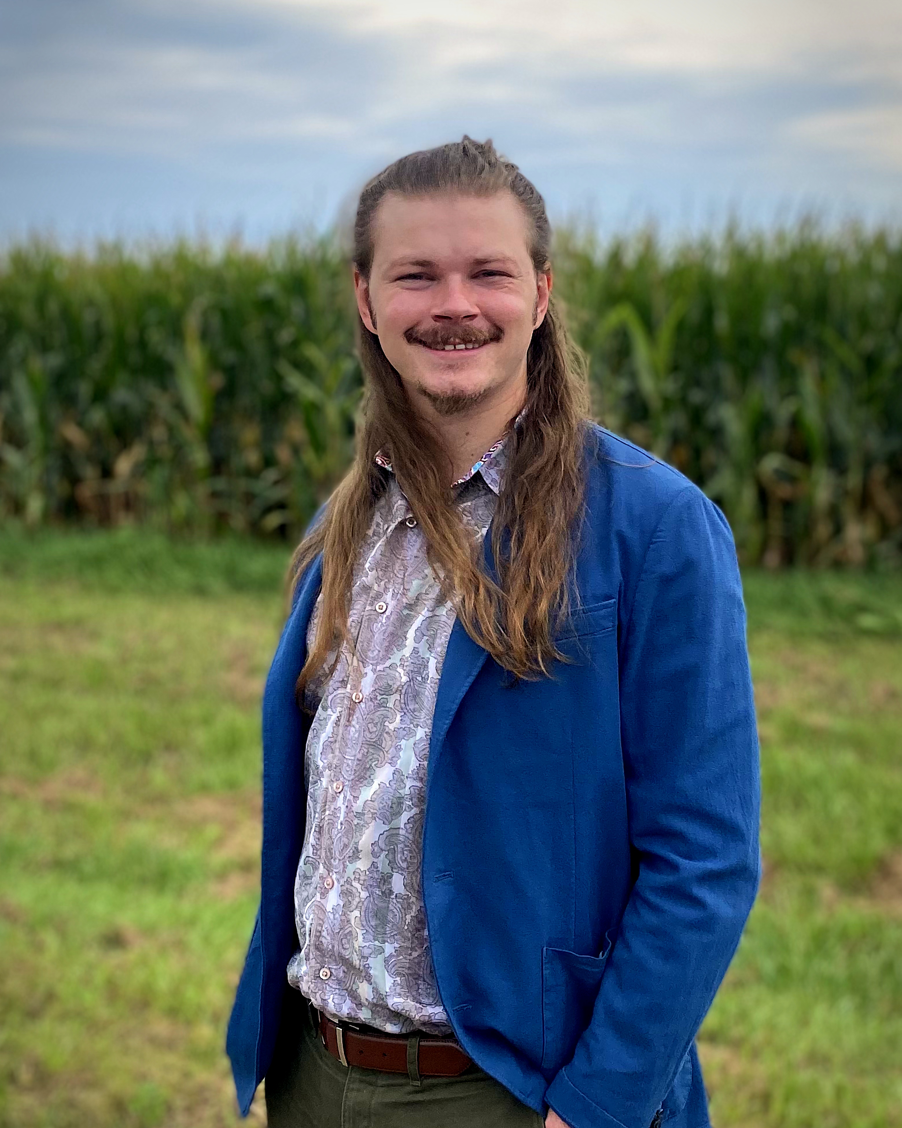 Jadyn Breland standing in front of a cornfield in Grinnell, Iowa